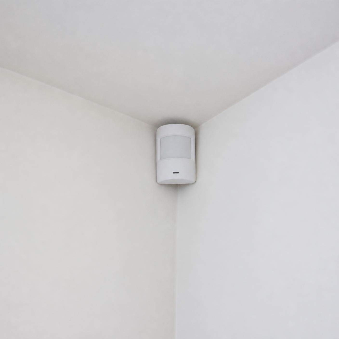 Bewegingsdetector van het inbraakalarm in de hoek van een ruimte
